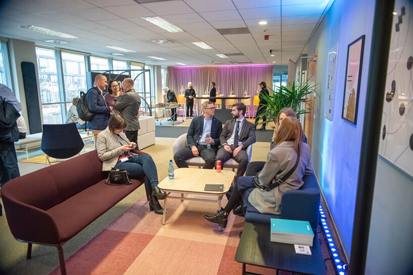 kilku gości siedzących przy stole podczas rozmów na otwarciu showroomu MDD