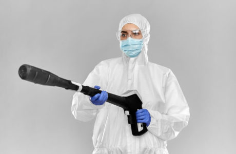 mężczyzna w białym stroju ochronnym i rękawiczkach ochronnych z ozonatorem