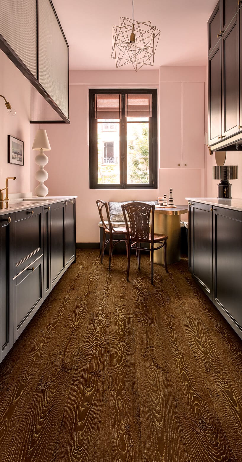 ciemna podłoga laminowana Quick-Step w różowej kuchni z czarnymi frontami szafek