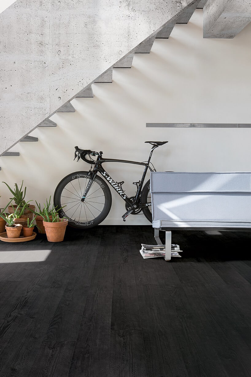 czarna podłoga laminowana Quick-Step w holu z biała ławką pod schodami i czarnymi rowerem kolarskim S-WORKS