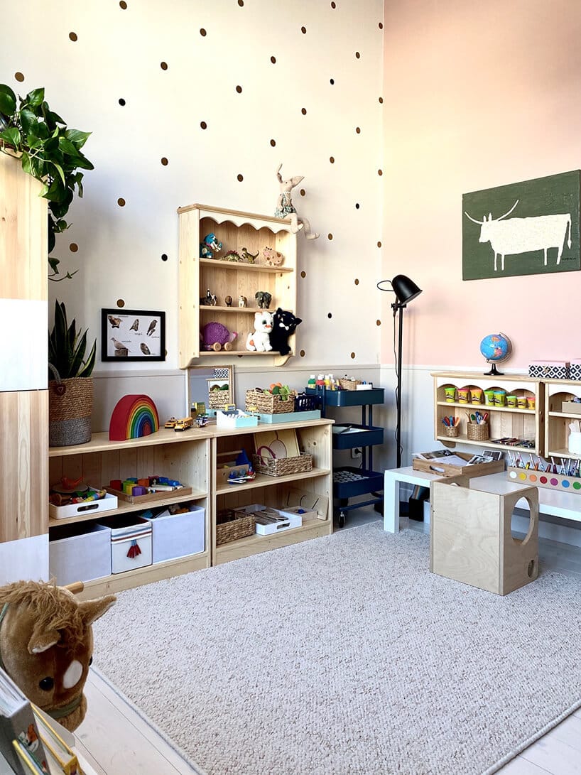 pokój dziecięcy w stylu Montessori od KUUDOdrewniane meble na zabawki wraz z wiszącą szafką na beżowej ścianie w kropki