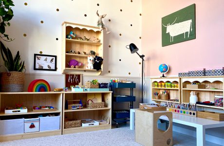 pokój dziecięcy w stylu Montessori od KUUDO drewniane szafki z zabawkami obok białego niskiego stolika