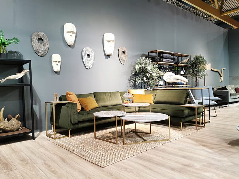 ciemno zielona sofa od Primavera Furniture z dosuwanymi stolikami nad siedzisko i oparcia