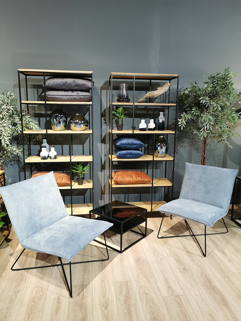 dwa niebieskie krzesła od Primavera Furniture przy małym czarnym stoliku ze szklanym czarnym blatem