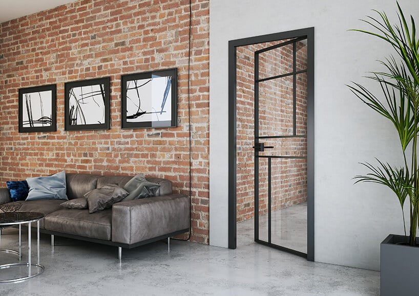 dwrz z połączeniem szkła oraz metalowej czarnej konstrukcji na ścianie z starej cegły ze srebrzystą kanapą oraz lustrami w ramach