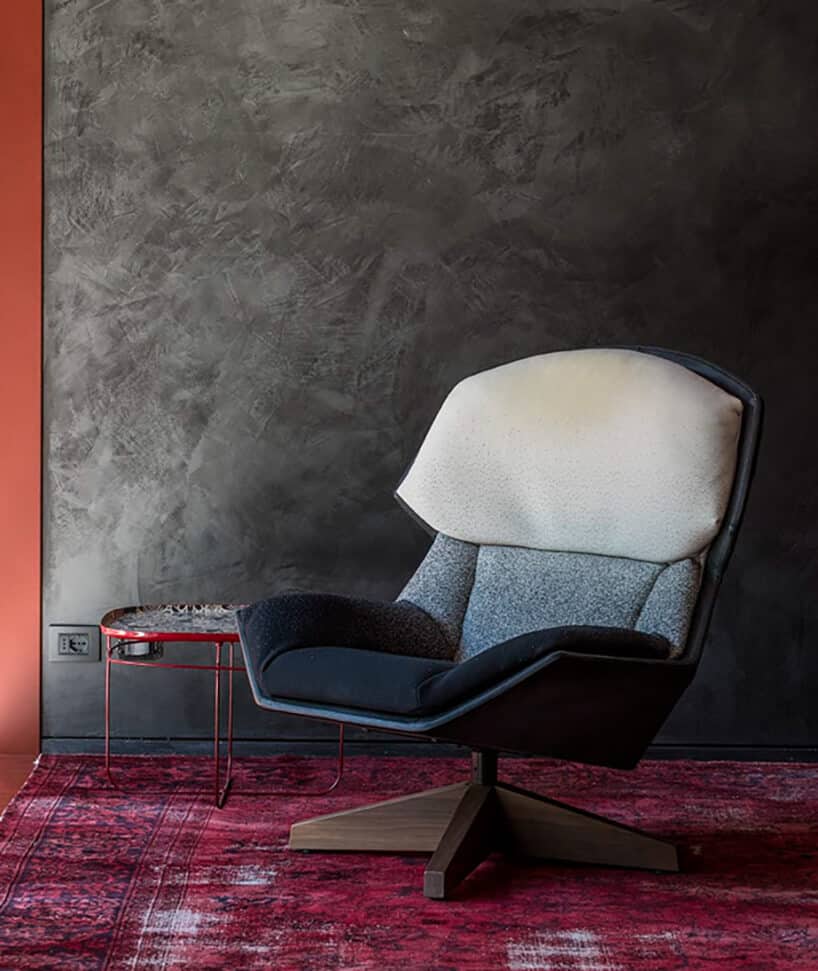 elegancki fotel Fotel Clarissa od Moroso z siedziskiem w odcieniach niebieskiego koloru na różowym dywanie na tle szarej ściany