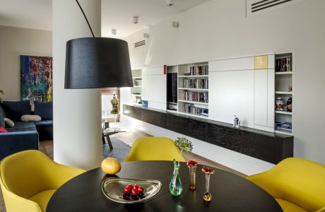 czarny okrągły stół z żółtymi krzesłami na tle białego apartamentu z czarnym wstawkami