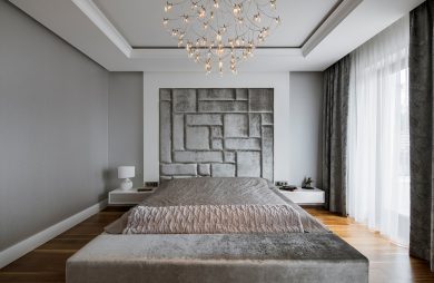 elegancka biało szara sypialnia z dużym łóżkiem ze srebrną narzuta pod wyjątkowym żyrandolem