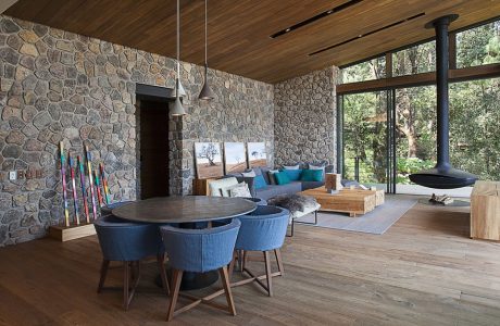 duży salon na ranczu z drewnianą podłoga i sufitem oraz kamienną ścianą