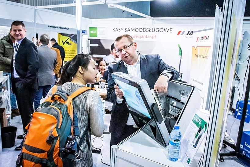 mężczyzna podczas prezentacji urządzenia jednemu z odwiedzających na RetailShow