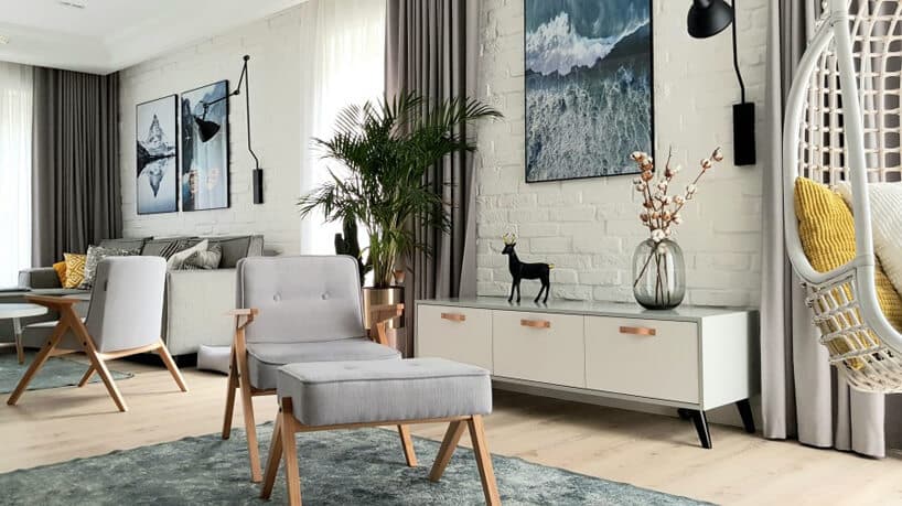 jasny salon w stylu skandynawskim z ceglanymi ścianami pomalowanymi na biało jako tło dla szarego fotela z podnóżkiem 