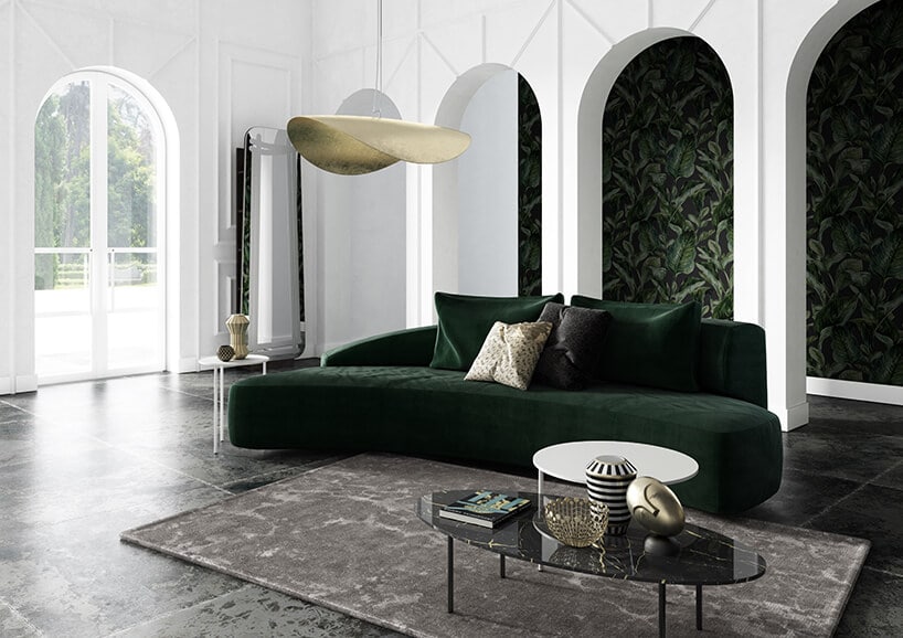 białe wnętrze z filarami i tapetą w motywie liści oraz ciemno butelkowo zieloną kanapą