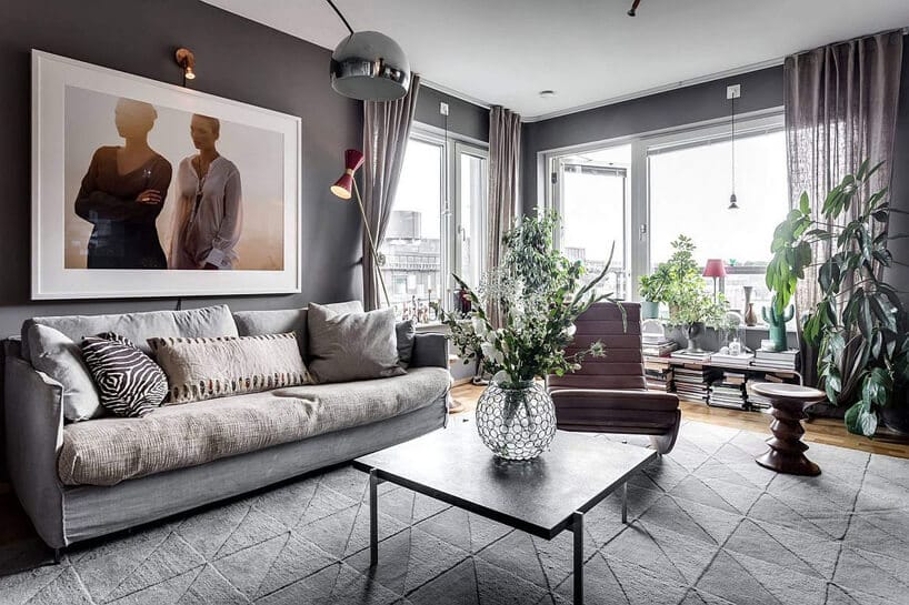 szary salon z drewnianą podłogą szarą sofą na tle dużych okien