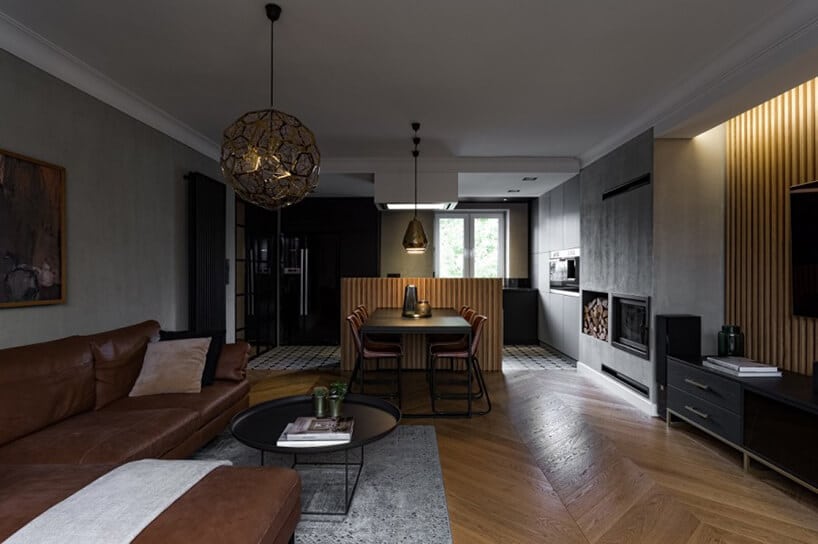 ciemno brązowo sofa narożna przy czarnym metalowym stoliku na tle ciemnego stołu jadalnego