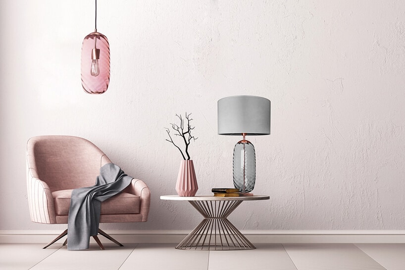 różowy fotel pod różową lampą obok niskiego stolika z lampą i wazonem