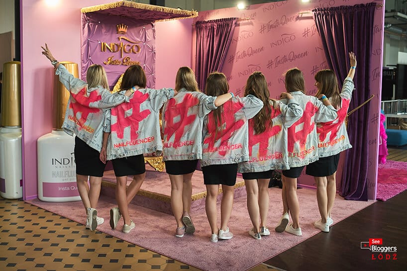siedem kobiet w dżinsowych kurtkach na tle różowego stoiska Indigo na See Bloggers 2019