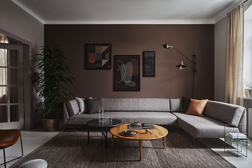 elegancki ciemny salon z dużą szarą narożną sofą na przy dwóch niskich okrągłych stolikach na szarym dywanie