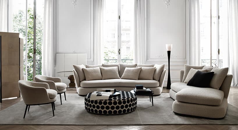 beżowa sofa Apollo od Maxalto bez nóżek jak tło dla białego dużego siedziska w czarne kropki na tle wysokich okien