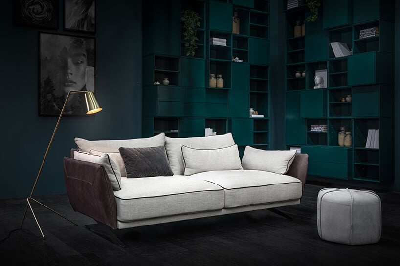elegancka sofa Monroe Max od MTI Furninova z beżowym siedziskiem i oparciem ze śliwkowymi bokami na tle zielonej wysokie zabudowy
