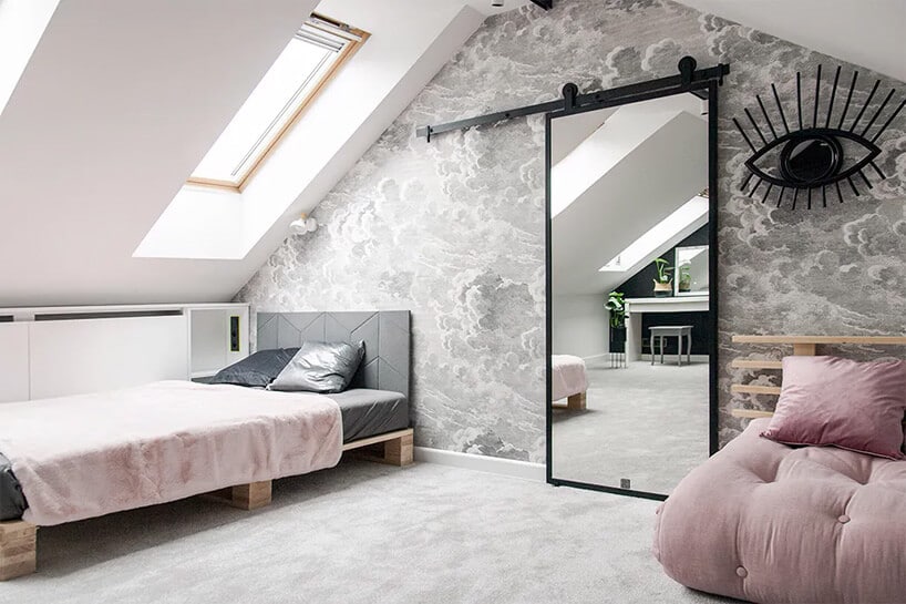 jasno pudrowo różowe łóżka w pokoju na poddaszu z przesuwnymi drzwiami z lustrem