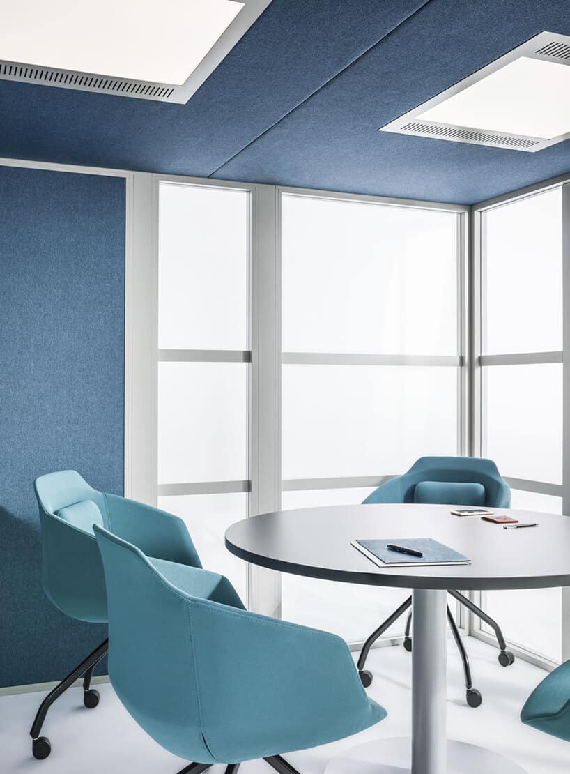 wnętrze Wnętrze Hako Meeting Room od MDD boxu w open space z okrągłym białym stolikiem i niebieskimi fotelami na kółkach