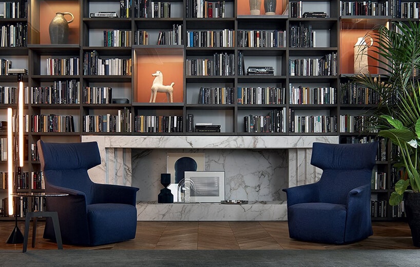 salon z dwoma eleganckimi niebieskim fotelami na tle kamiennego kominka i ściany pełnej książek