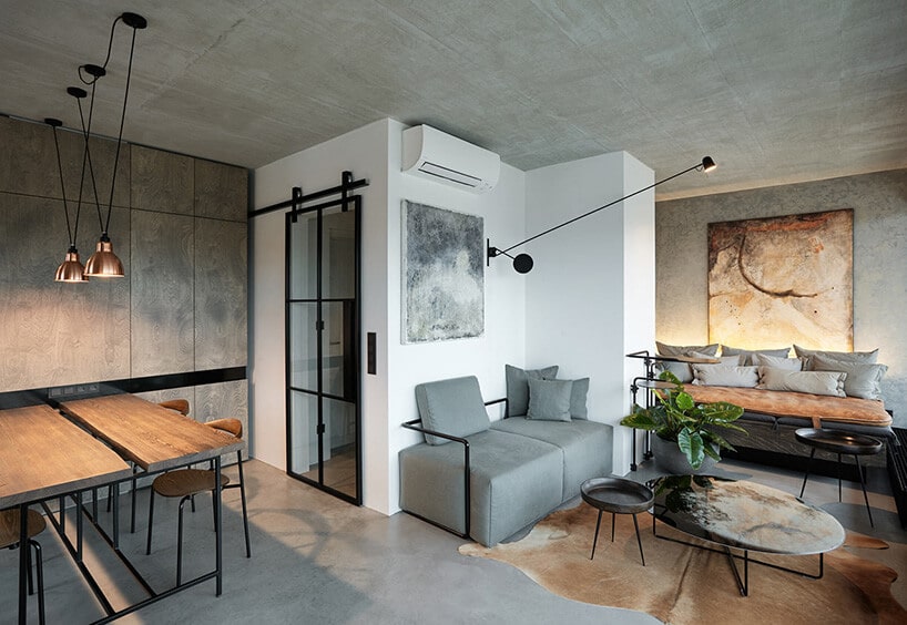 małe loftowe wnętrze z betonowymi ścianami oraz dodatkami w kolorze szary wraz z drewnem