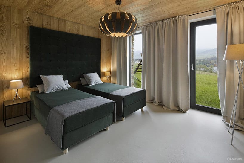 przestronna sypialnia wykończona drewnem dwoma łóżkami