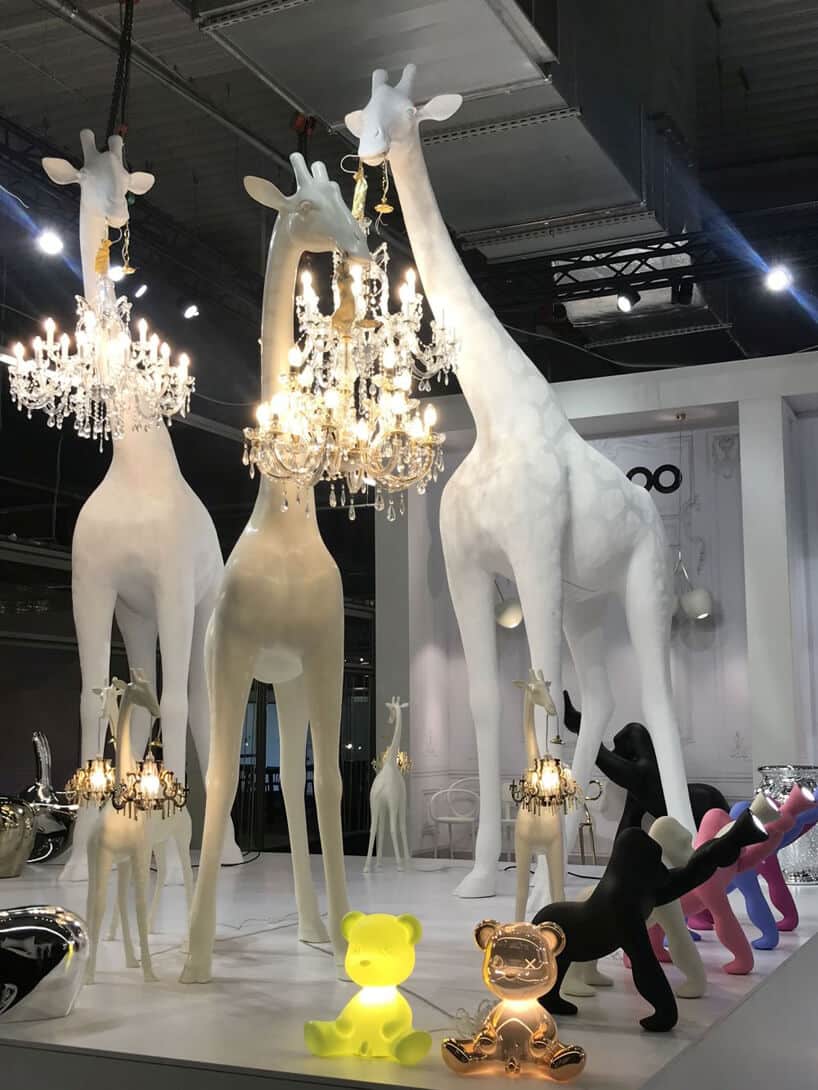 trzy białe duże żyrafy trzymające żyrandole na stosiku Stoisko QeeBoo podczas Warsaw Home 2019