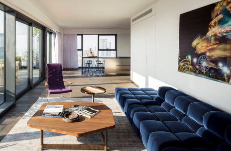 elegancki apartament od Anderman Architects wyjątkowy salon z dużą niebieską sofą i fioletowy fotelem przy niskim drewnianym stoliku