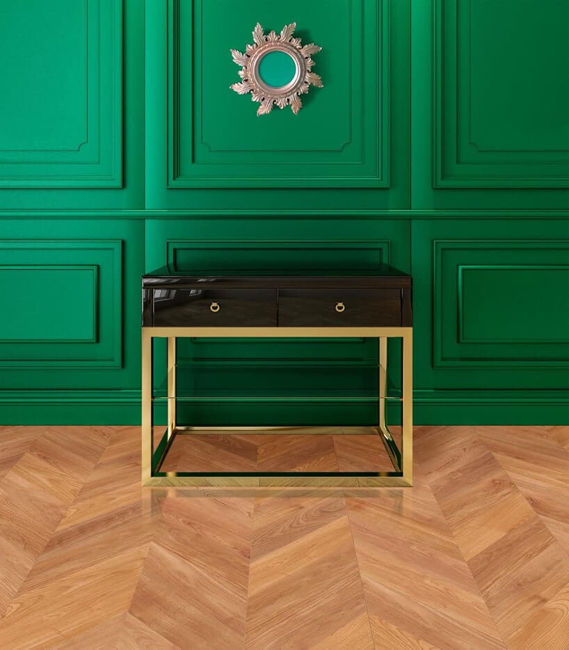 ciemna szafka na złotym stelażu na drewnianej podłodze na tle zielonej ściany