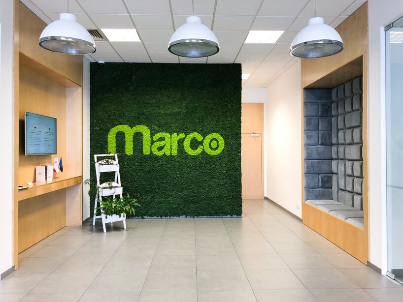 aranżacja wnętrza open space z zieloną ściana z napisem Marco obok miejsca do siedzenia osadzonego w ścianie