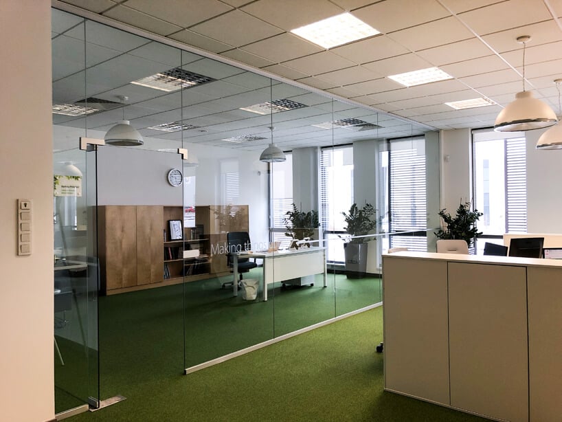 biało zielona aranżacja open space z oddzielonym szkłem biurem