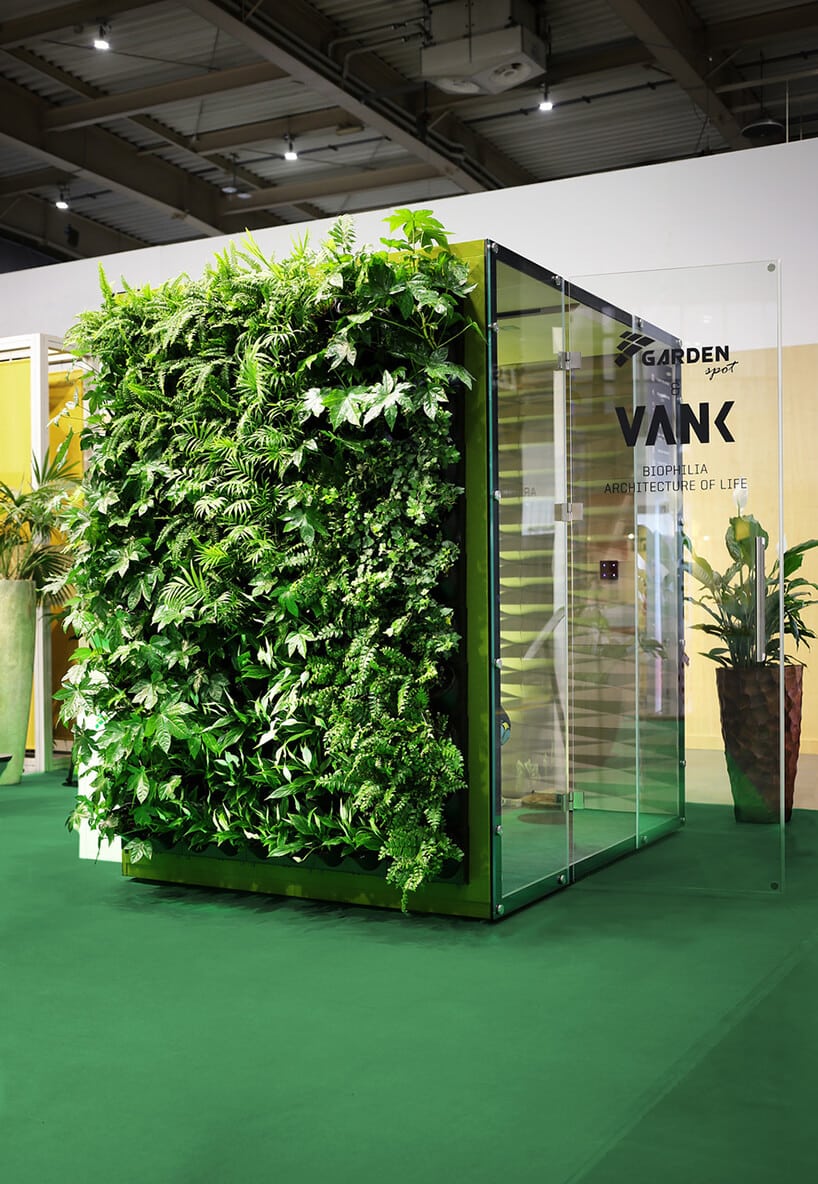 zielony box akustyczny VANK_WALL JUNGLE z otwartymi szklanymi drzwiami i roślinami na zewnętrznej ścianie