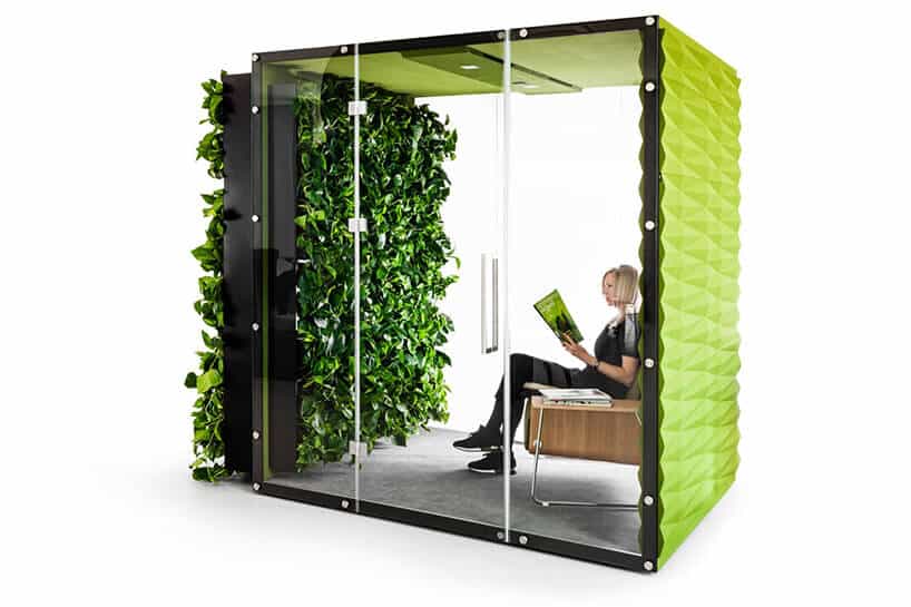 kobieta siedząca zielonym boxie akustycznym VANK_WALL JUNGLE z otwartymi szklanymi drzwiami i roślinami na zewnętrznej ścianie