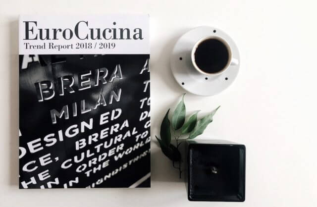 książka EuroCucina obok filiżanki z kawą oraz małego kwiatka