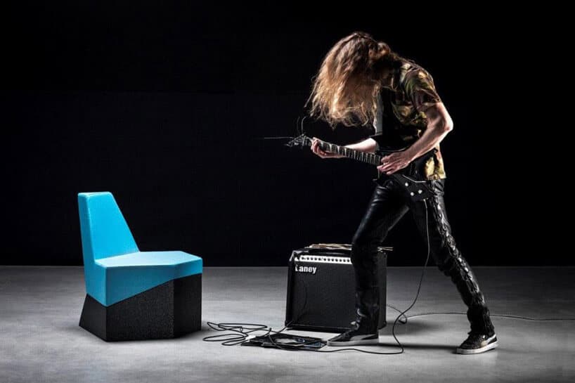niebieskie krzesełko czarny wzmacniacz gitarzysta ubrany na czarno z czarną gitarą elektryczną w ciemnym pomieszczeniu z szarą podłogą