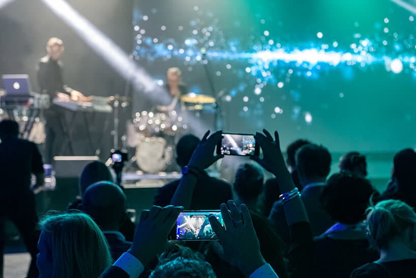 ludzie nagrywający koncert smartfonami na tle sceny