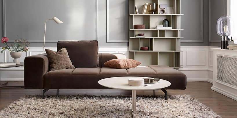 brązowa sofa Amsterdam od BoConcept w aranżacji salonu na tle szarej i białej ściany