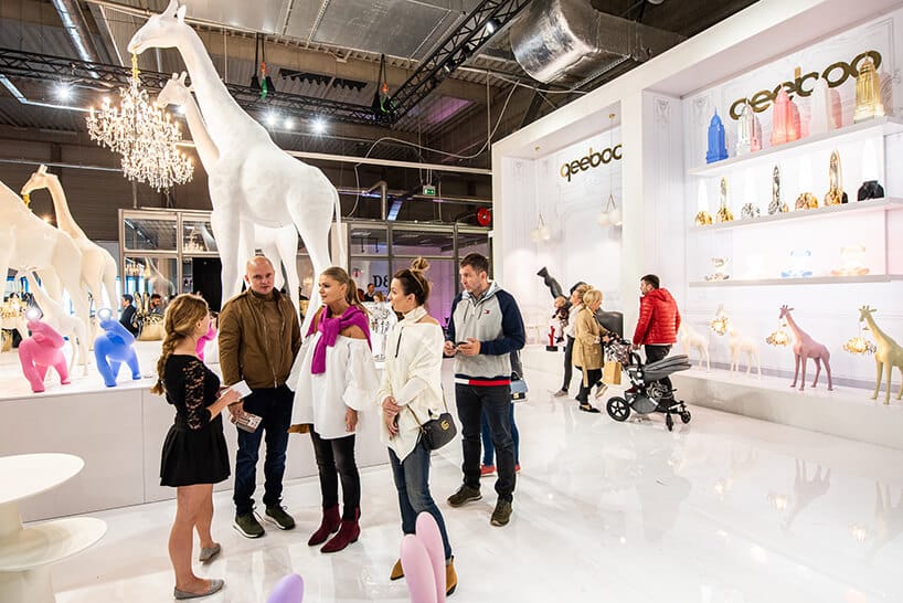 odwiedzający Warsaw Home 2019 pośród białych stoik i białych żyraf od qeeboo