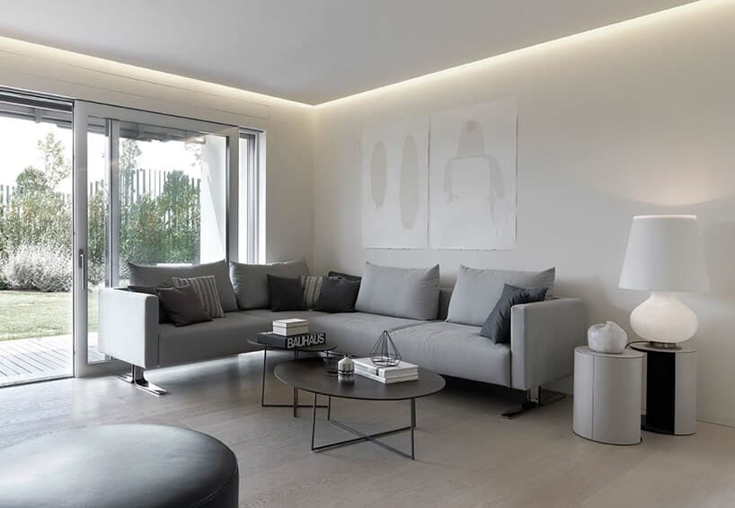 wnętrze w stylu hygge szara sofa narożna przy dużych drzwiach na ogród