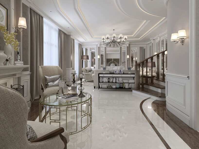 eleganckie białe wnętrze z biała kamienną podłogą z brązowym pasem pod ścianami wyjątkowym okrągłym stolikiem ze złotych metalowych prostokątów