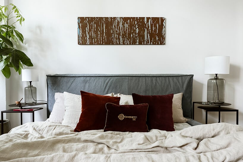 łóżko z biała pościelą oraz bordową poduszką na środku z szarym zagłowiem