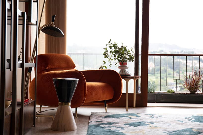 wnętrze wyjątkowego showroom covet valley elegancki pomarańczowy fotel z niskim oparciem obok wyjątkowego stolika w kształcie klepsydry ze złotą opaską