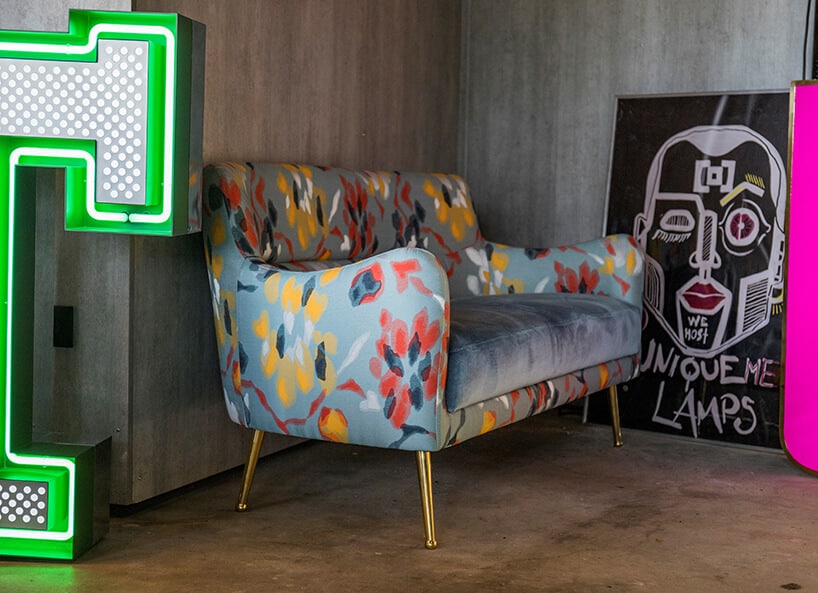 wnętrze wyjątkowego showroom covet valley niebieska sofa z kolorowymi plamami przy nwooczesnym plakacie pomiędzy neonami