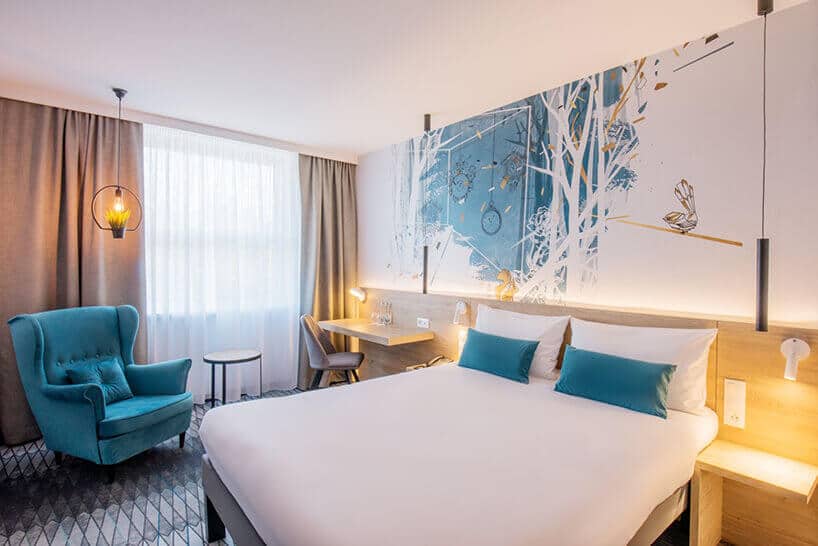 ibis Styles Santorini pokój hotelowy z łóżkiem i niebieskimi poduszkami