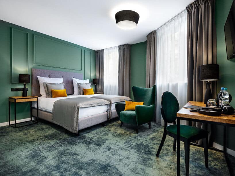 Wawel Queen pokój hotelowy z zielonymi ścianami , zielonym fotelem i żółtymi poduszkami