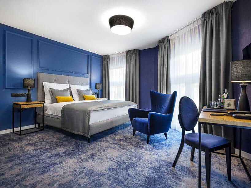 Wawel Queen pokój hotelowy z niebieską wykładziną,, łóżkiem i niebieskim fotelem