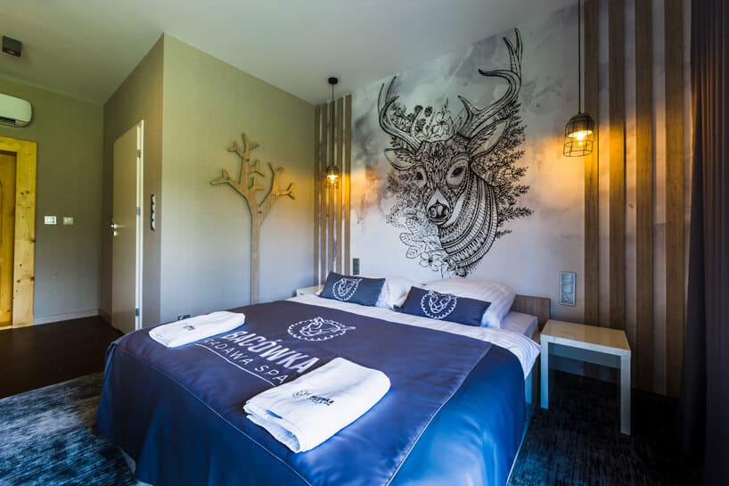 pokój hotelowy w Bacówka Radawa & SPA dużymi łóżkiem i grafiką jelenia na ścianie