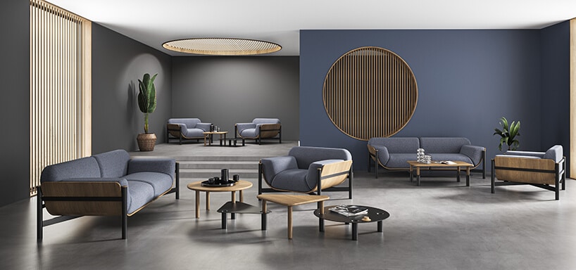 elegancka niebieska sofa i fotel na białych nogach z czarnymi i brązowymi stolikami